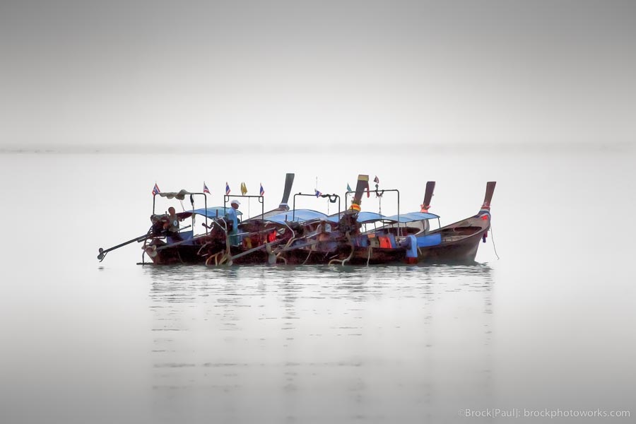 Four boats floating off an island shore in Thailand
